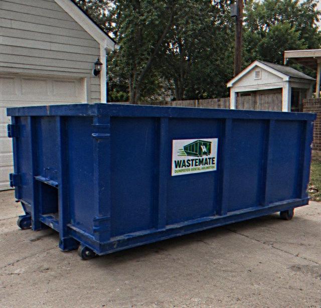 Dumpster parked on a home driveway beside the garage