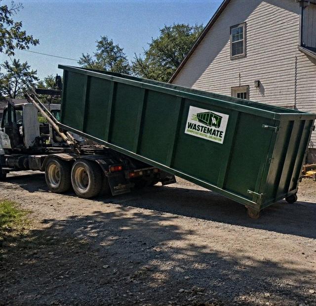 Dumpster being rolled off the delivery truck at a property